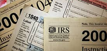 A pile of tax-related documents sits atop each other in a chaotic mess.