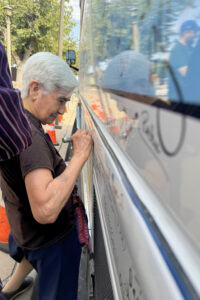 Sr. Maria Engracia Robles, ME, of Kino Border Institute signs the Bus during the 2024 Nuns on the Bus & Friends site visit to the U.S-Mexico Border. Photo: Jacob Schatz, CCR Studios